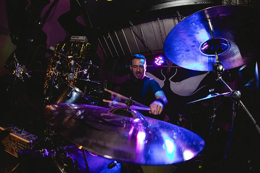 Baterista tocando detrás de un platillo azul y violeta